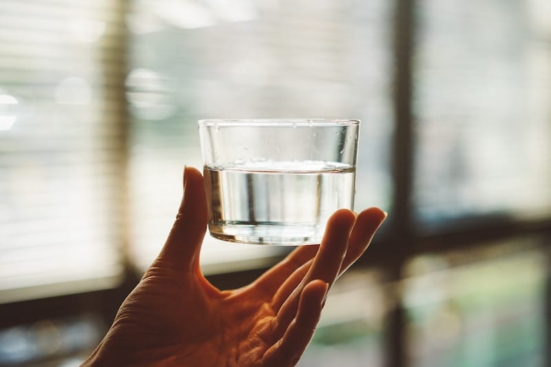 A person holding a half-filled glass of water.